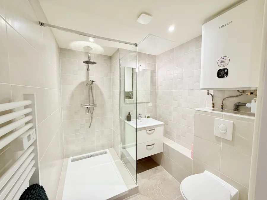 La salle de bain : douche à l'italienne, vasque et sèche-serviettes